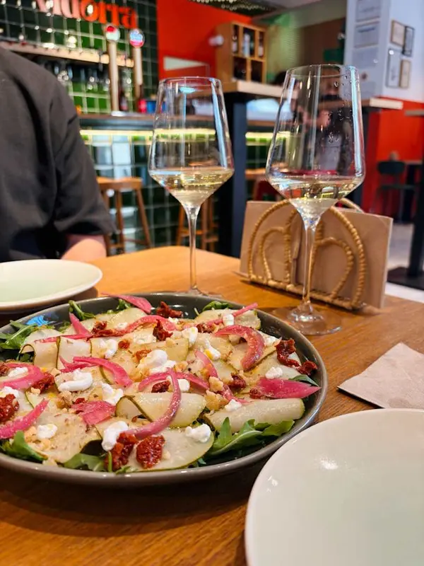 Carpaccio de pera amb cremós de formatge de cabra, nous, tomàquet sec, rúcula i vinagreta de mel