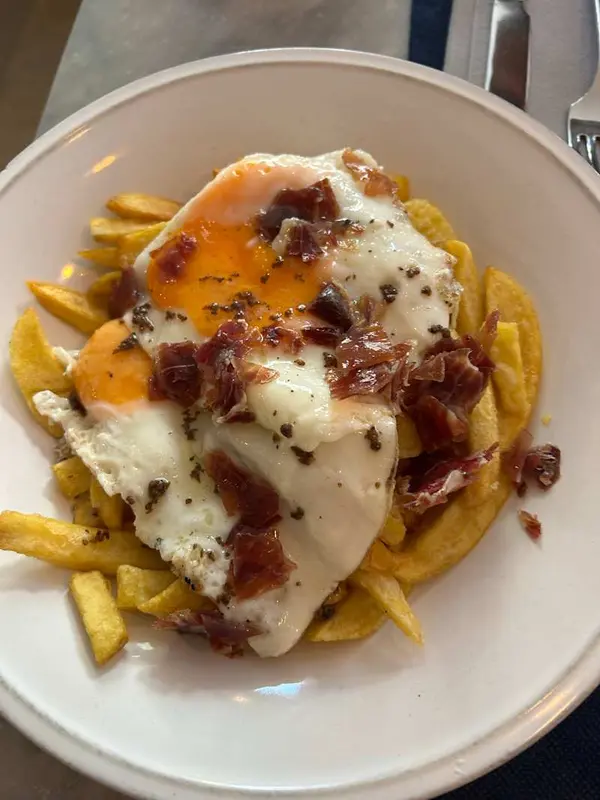 Huevos rotos con virutas de jamón ibérico y aceite trufado