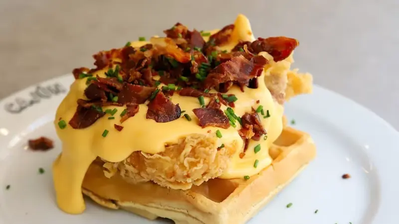 Pollo frito sobre waffle con cheddar y crispy bacon