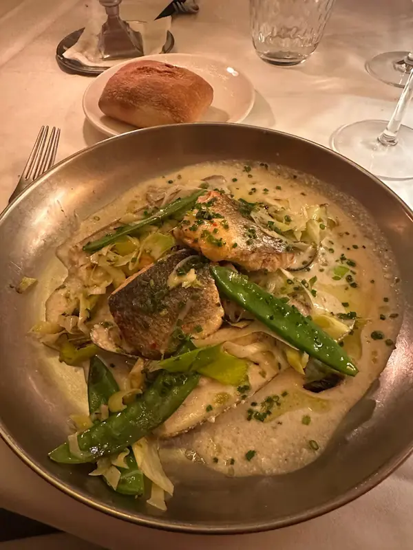 Lubina salvaje al vapor, ragú de puerro, tirabeques y moluscos a la crema de hinojo, reduccion de chardonnay y jengibre.