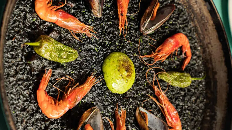 Arroz negro con gambas, mejillones, alioli de hierbas gratinado y pimientos del padrón