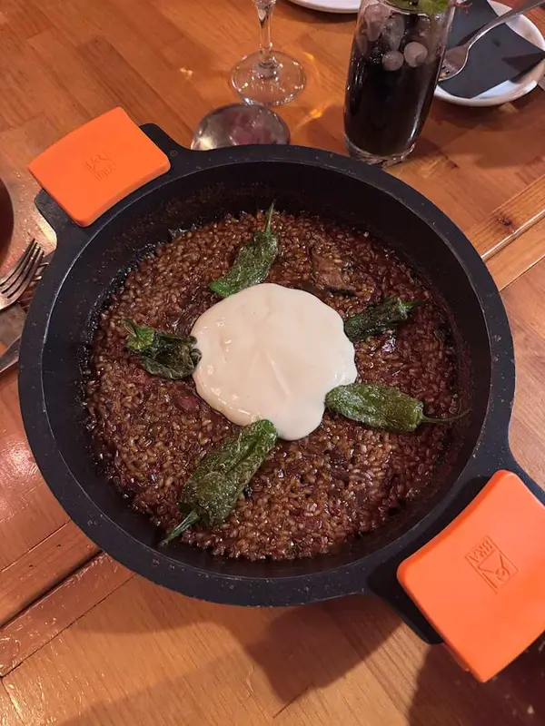 Arroz meloso de pato con setas, espuma de ajo asado y pimientos de padrón